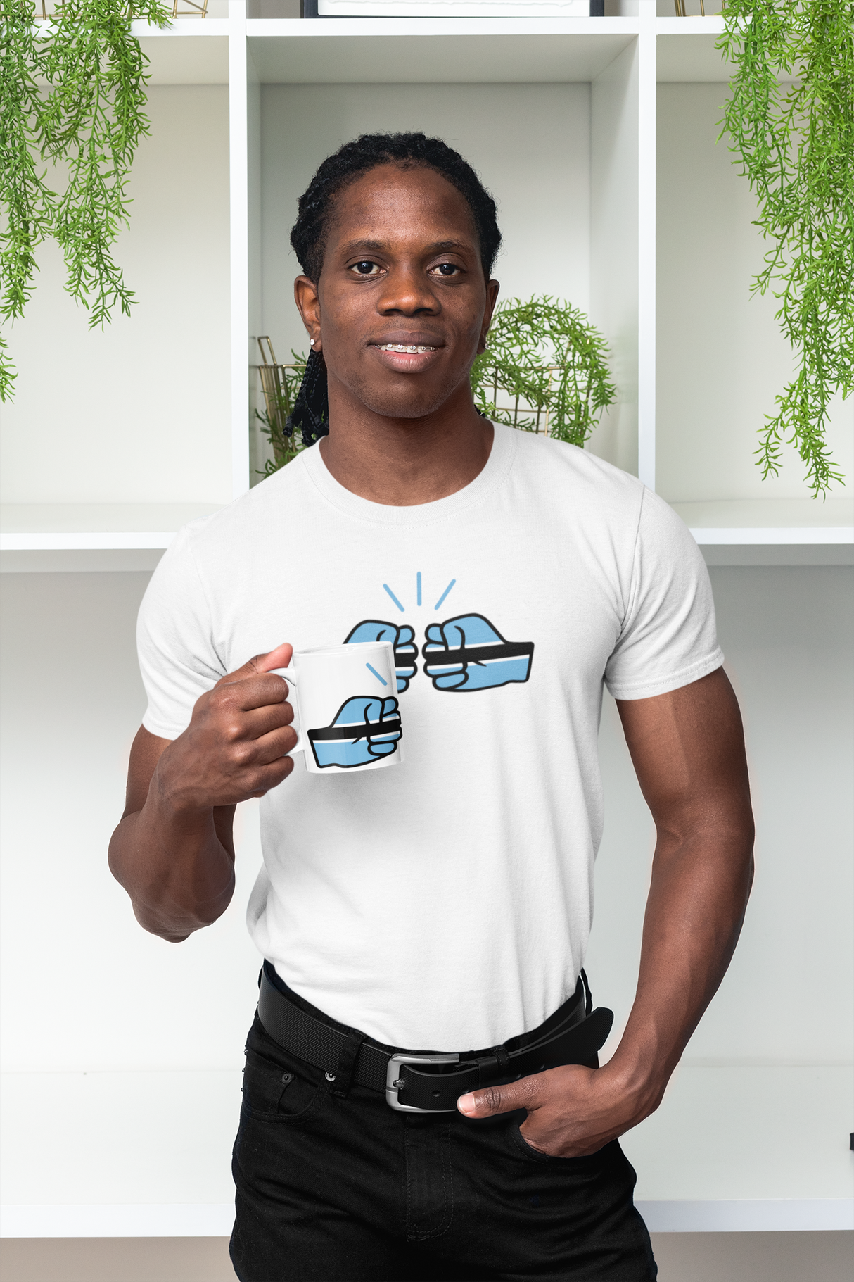 Man wearing a white t-shirt carrying a coffe mug with the We Run Tings Botswana design, standing in front of a white shelf with green plants.