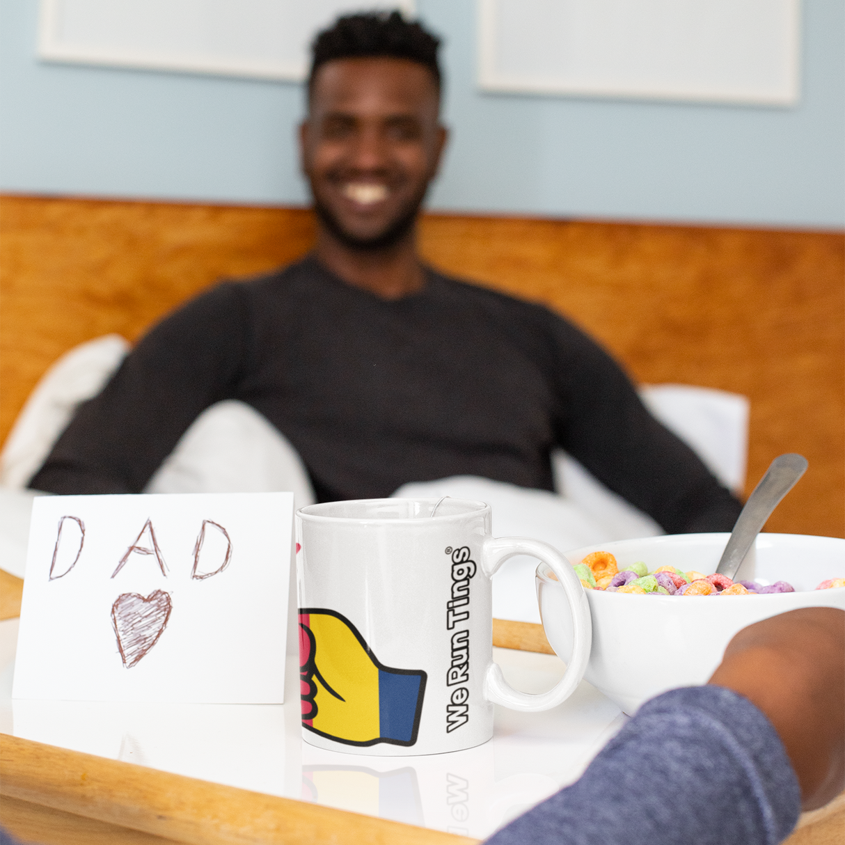 Man sitting at a table displaying a We Run Tings Chad themed coffee mug, a bowl of cereal and card labeled 'DAD'