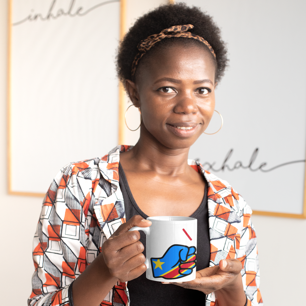 Woman holding a We Run Tings The Democratic Republic of The Congo (DRC) themed mug with a colorful design in an indoor setting