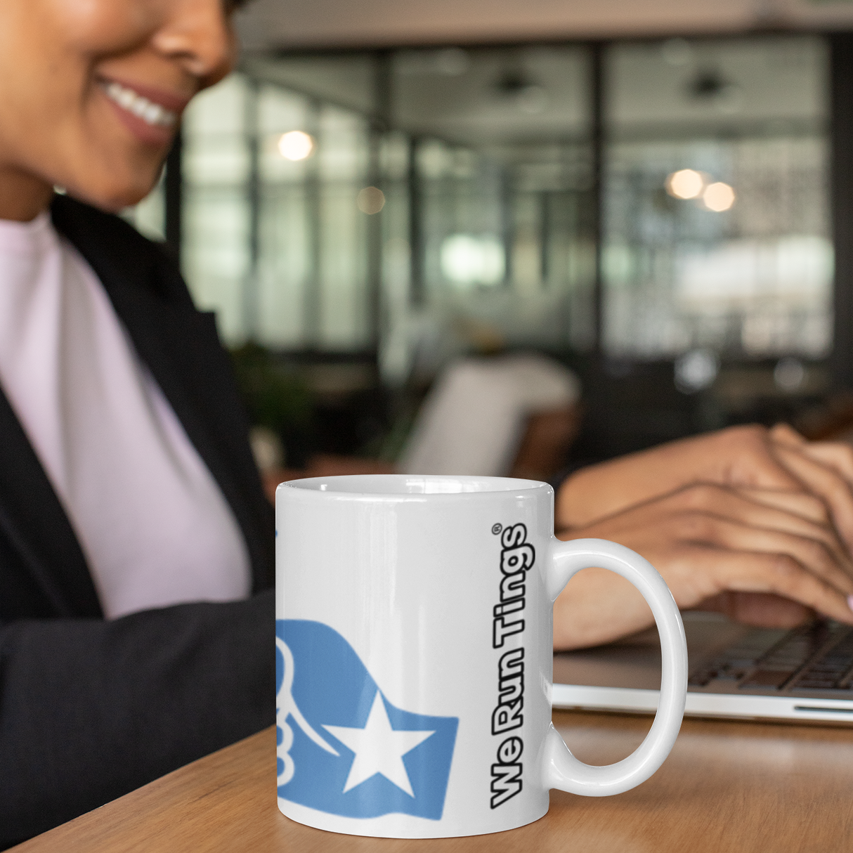 Woman in a professional sitting with a Somalian themed We Run Tings white ceramic coffee, tea mug sitting on a desk.