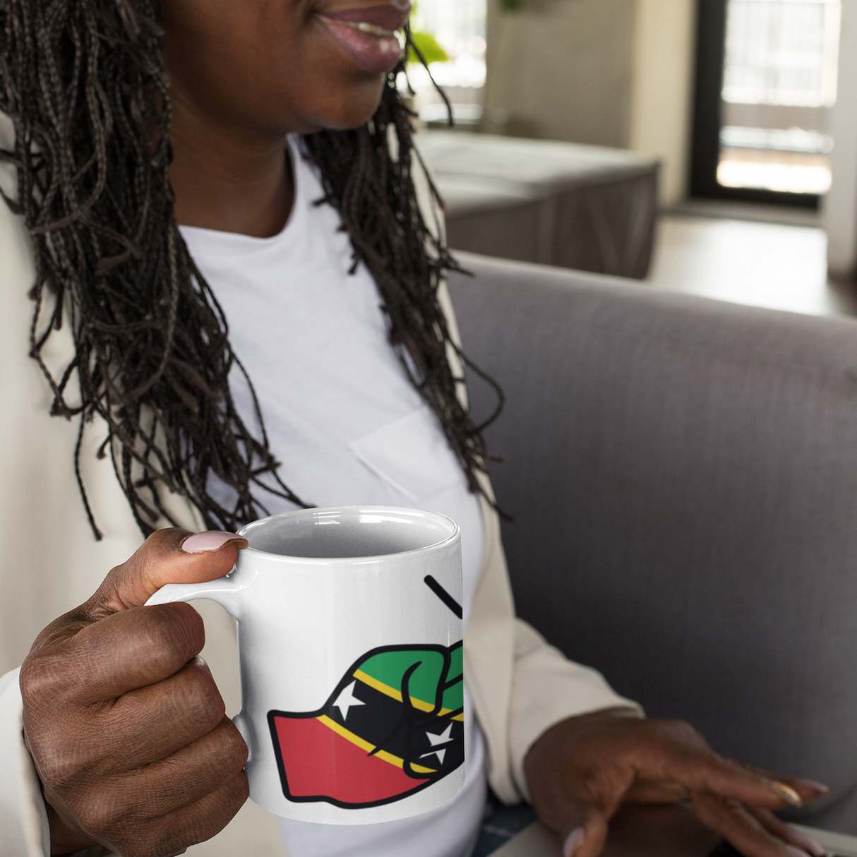 Woman holding a mug with a We Run Tings St Kitts, Kittitians & Nevisians Caribbean Theme design, using a laptop in a home setting