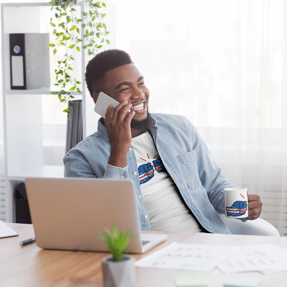 Man talking on phone holding a We Run Tings Cabo Verde, Cape Verde themed mug in an office setting