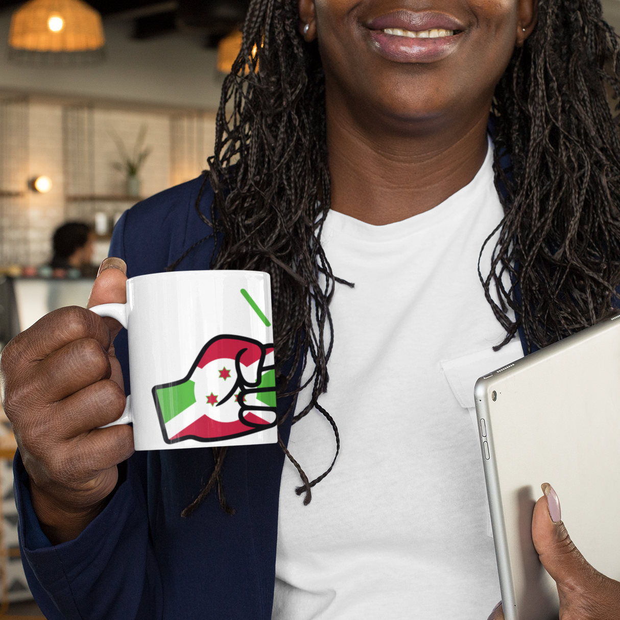 Woman holding a mug with a Burundi flag and We Run Tings logo and a tablet in an indoor setting