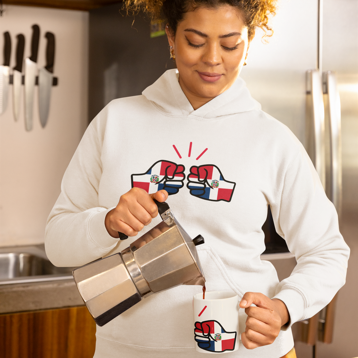 Woman pouring coffee into a white We Run Tings, Dominican Republic Mug wearing a hoodie with the matching logo