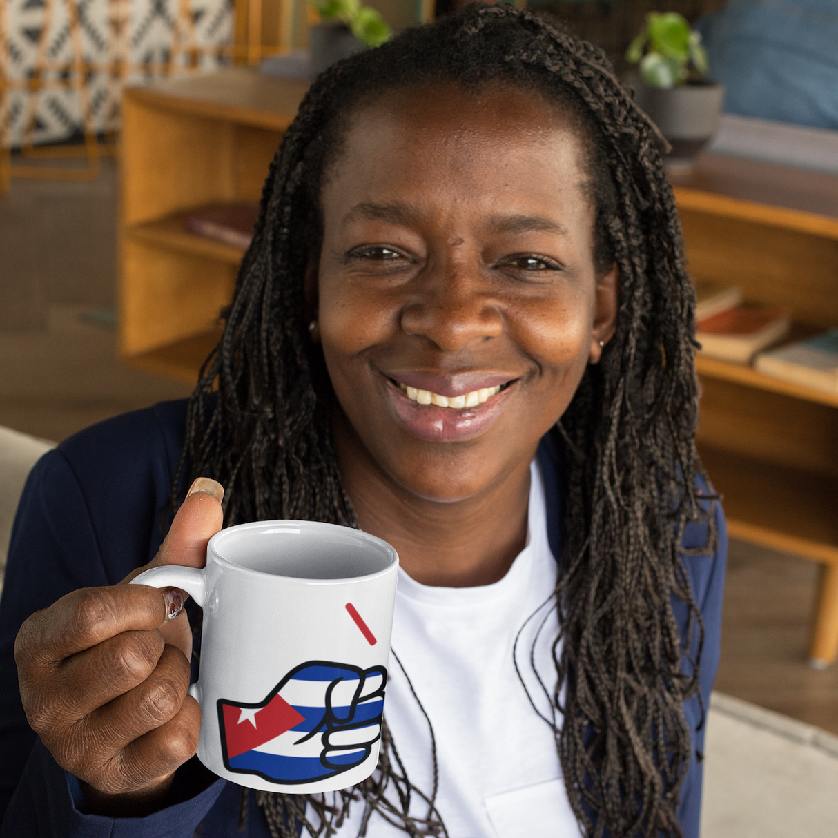 Person holding a mug with a design, sitting in a room with furniture and decor.