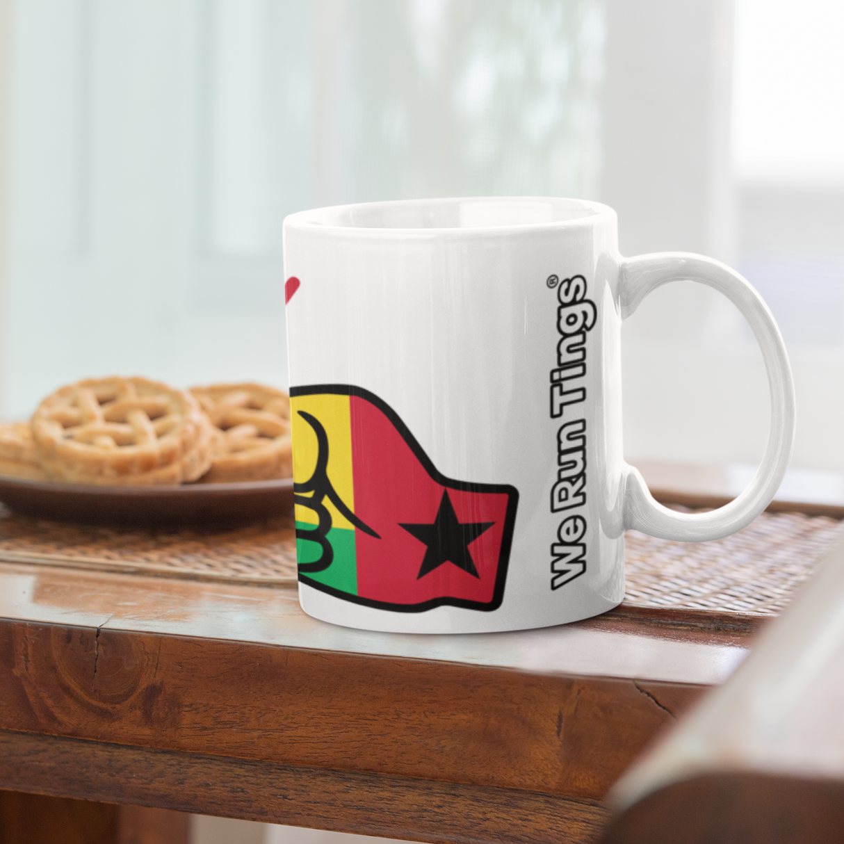 A glossy white ceramic mug with a graphic design of the flag of Guinea-Bissau and the brand logo of 'We Run Tings'. on a wooden table.
