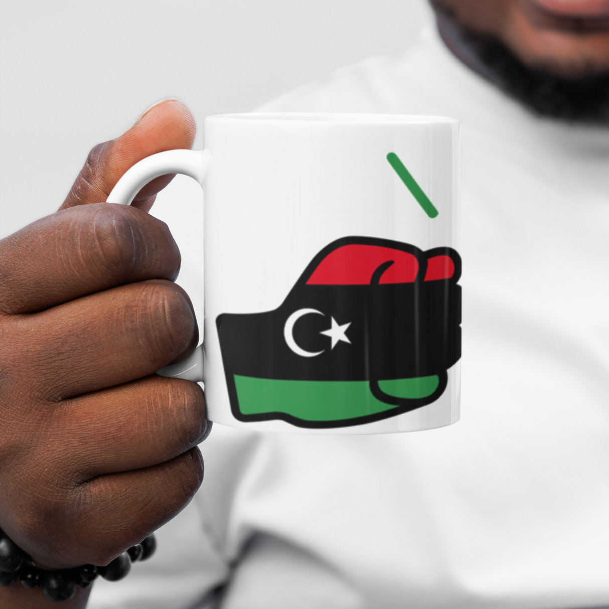 Person holding a We Run Tings Libya white ceramic mug with a design featuring a fist and flag, representing Libya.