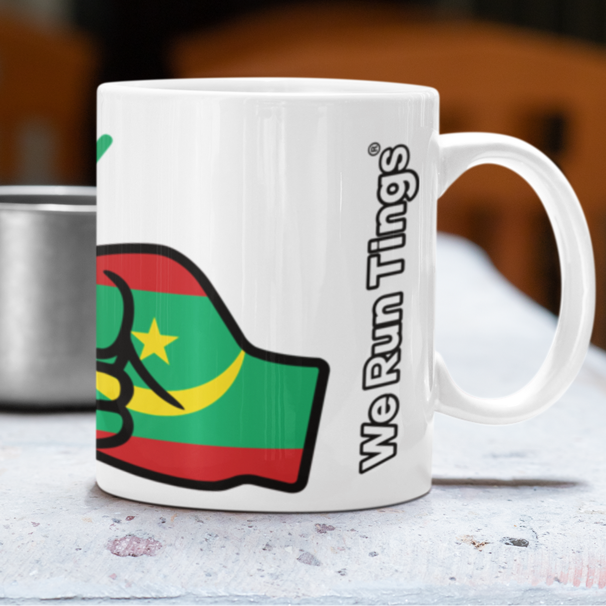 White ceramic We Run Tings, Mauritania tea, coffee, mug, cup with a colorful design and 'We Run Things' text on a table. Side view