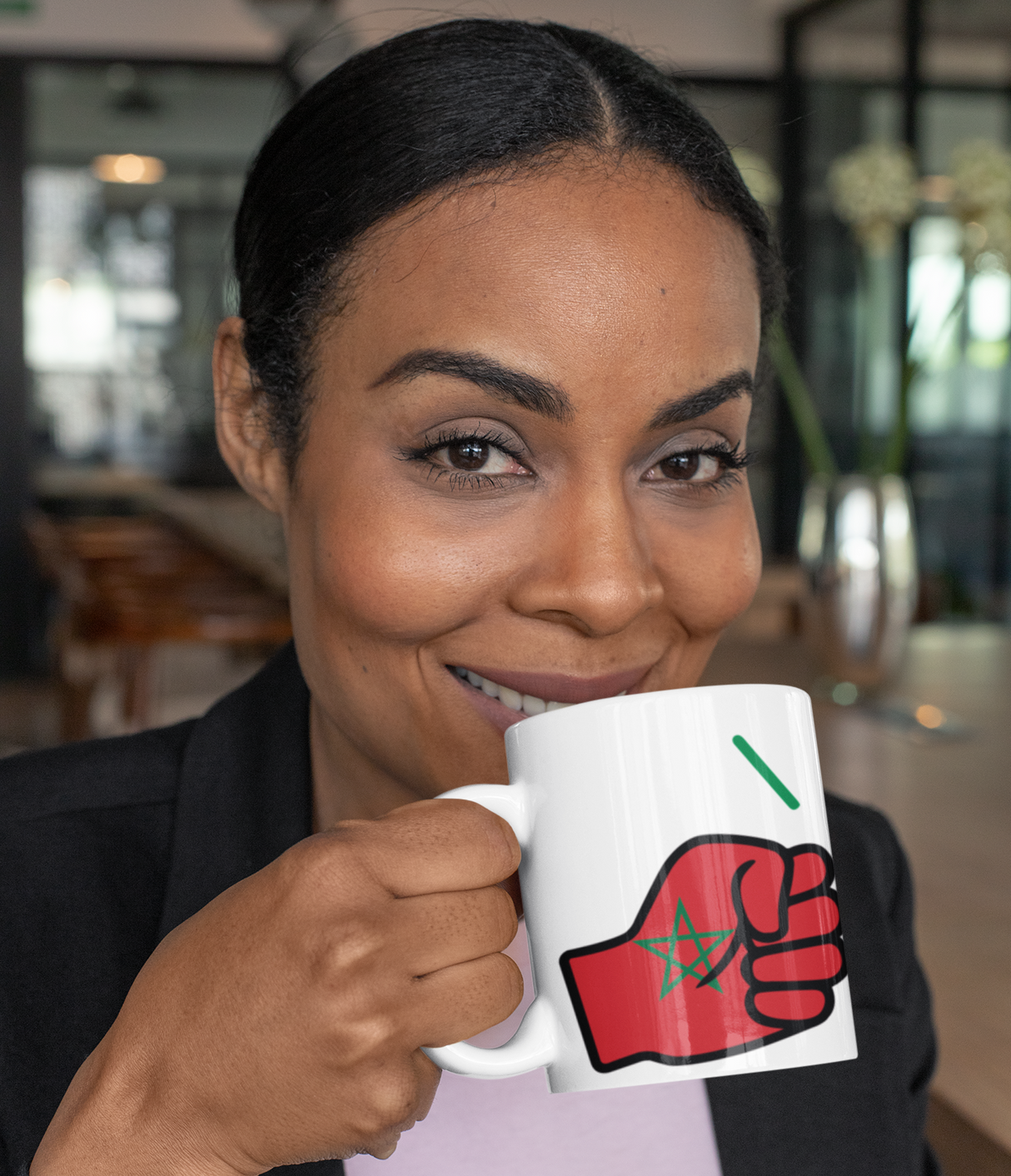 Woman holding a mug with a red and black fist design representing We Run Tings Morocco white ceramic tea, coffee, mug, cup in an indoor setting