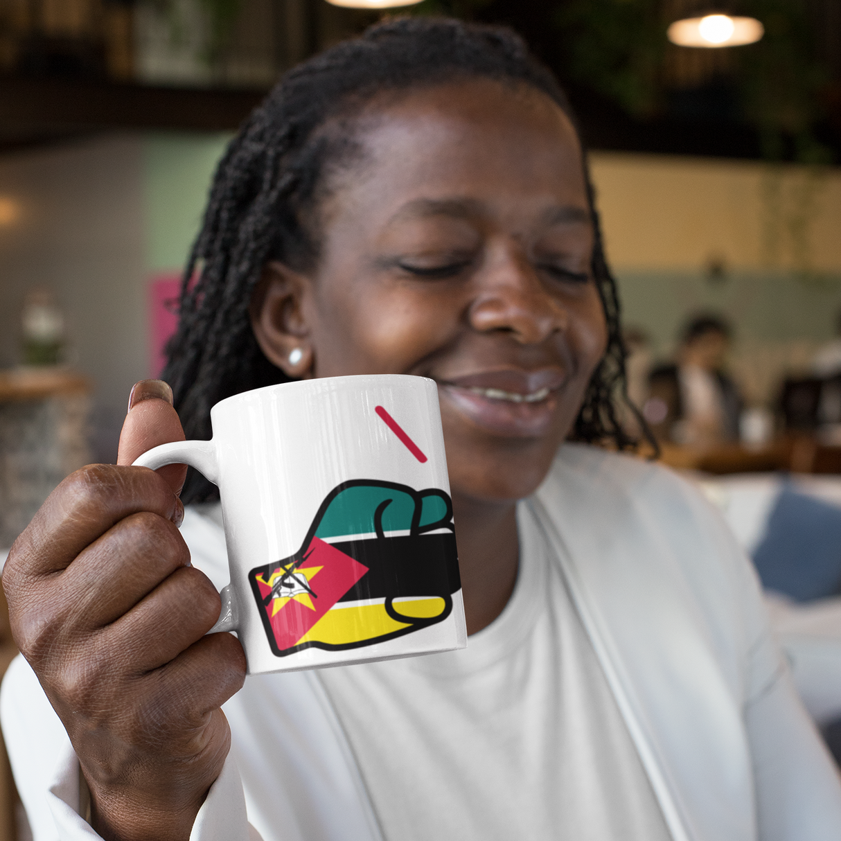 Woman holding a white ceramic We Run Tings tea, coffee, mug, cup with a design, sitting at a table with a laptop.