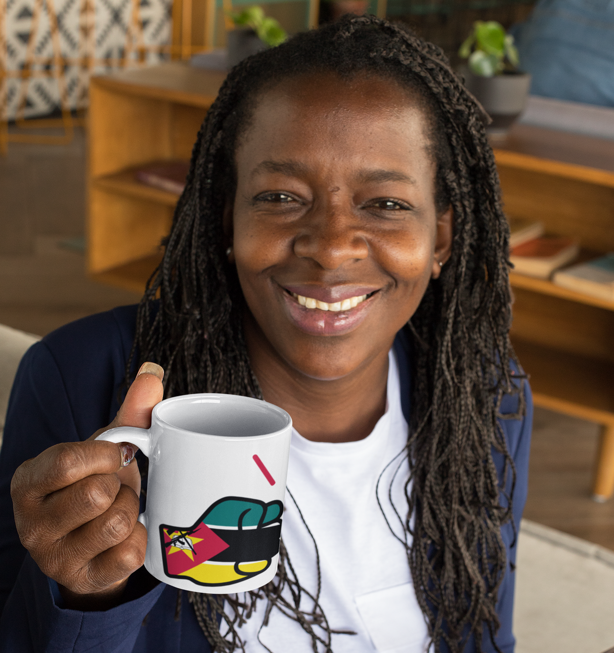 Woman holding a white ceramic We Run Tings Mozambique tea, coffee, mug, cup with a colorful design in a casual indoor setting