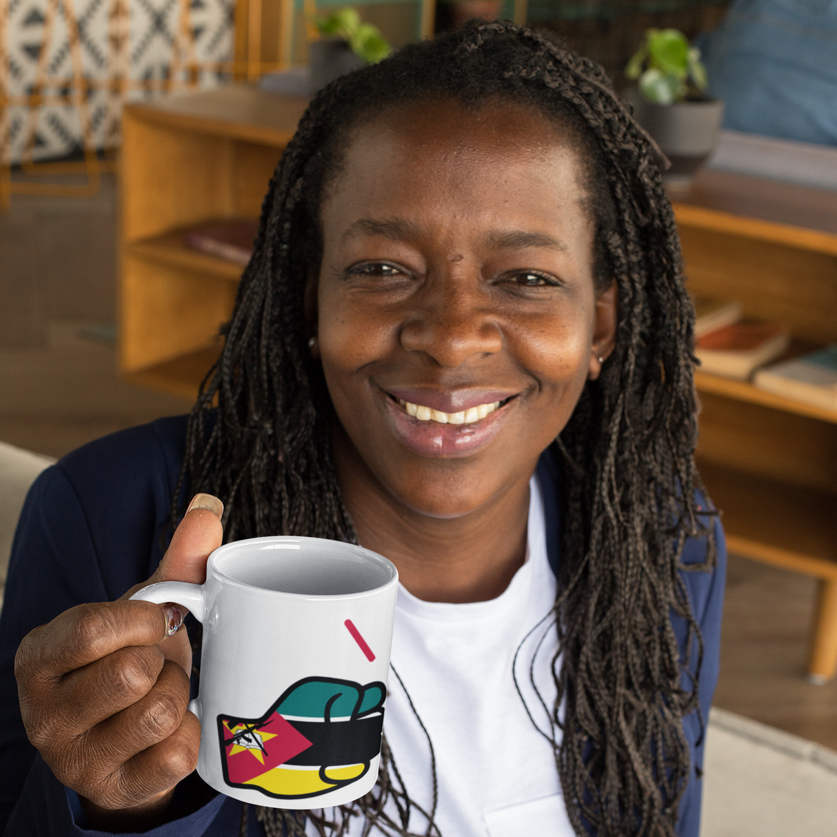 Woman holding a white ceramic We Run Tings Mozambique tea, coffee, mug, cup with a colorful design in a casual indoor setting