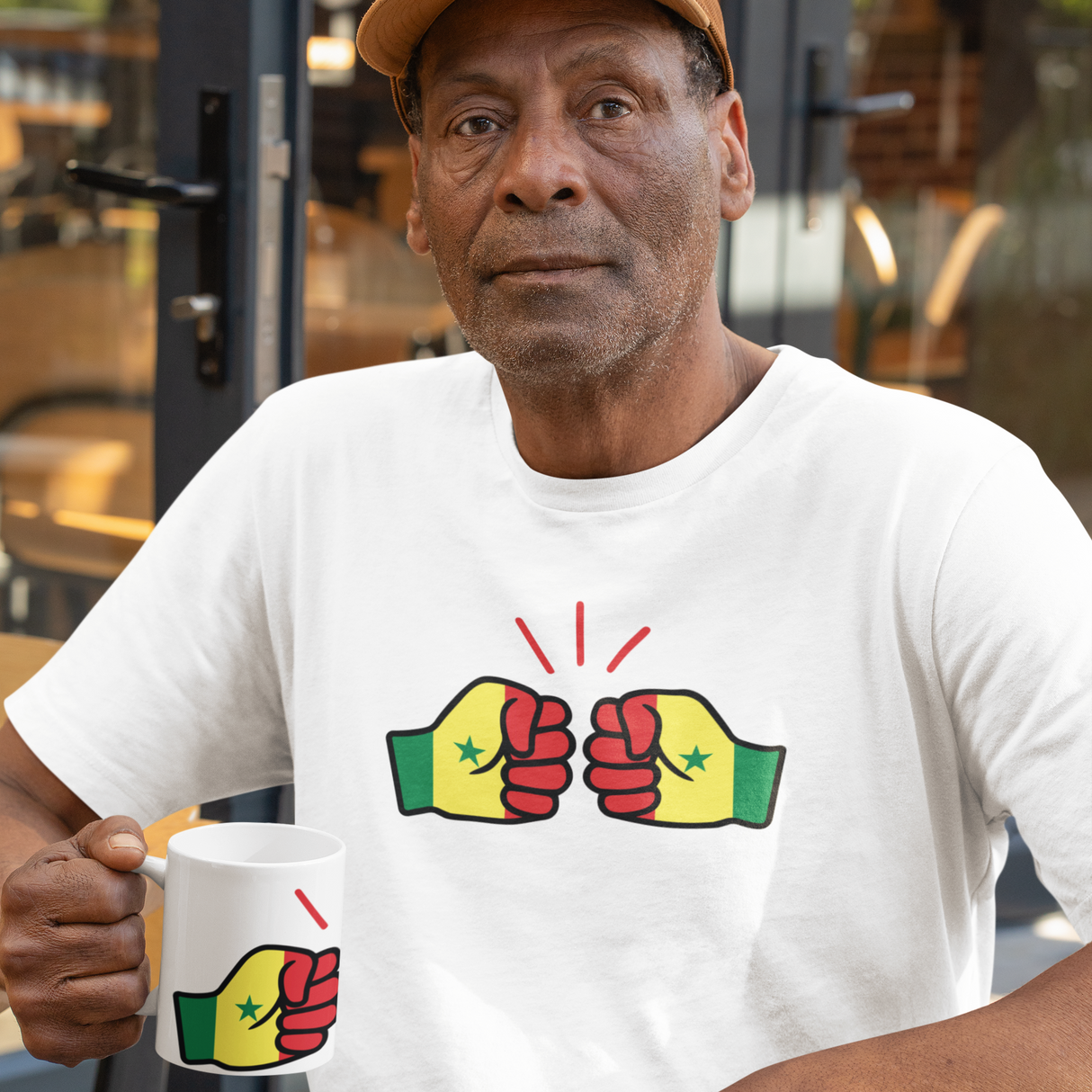 African Man showcasing We Run Tings Senegal merchandise a white t-shirt with colorful graphic design, holding a mug in an indoor setting.