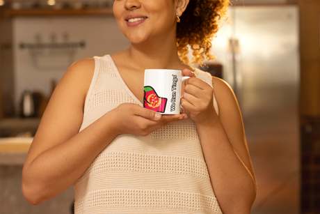 Woman holding a We Run Tings Eritrea themed ceramic mug with a visible brand logo in a kitchen setting
