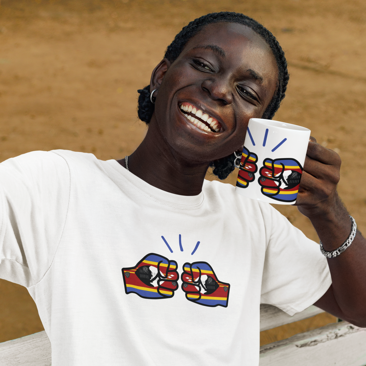 Person wearing a white t-shirt with colorful graphic design, holding a We Run Tings branded Eswatini themed cup outdoors.
