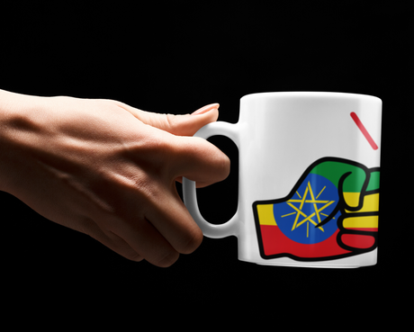 Hand holding a We Run Tings Ethiopia mug with a colorful design on a black background