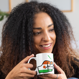 A curly haired woman holding a glossy white ceramic We Run Tings Niger tea, coffee mug, cup with a graphic design of a fist and the colors of the flag of Niger. Front view on a white background