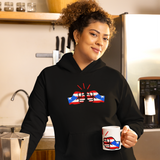 Woman wearing a black hoodie with a design, holding a mug in a kitchen. Both feature the brand logo of We Run Tings in the flag of Puerto Rico