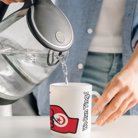 Person pouring water from a kettle into a mug with a visible brand logo of We Run Tings featuring the flag of Tunisia 
