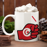 White mug with a We Run Tings Logo and flag of Tunisia design filled with hot chocolate and marshmallows on a wooden surface.