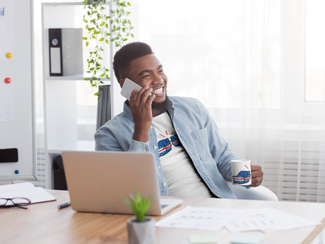Man talking on phone holding a We Run Tings Cabo Verde, Cape Verde themed mug in an office setting