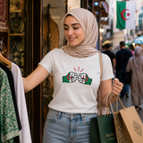 Woman wearing a white t-shirt with the We Run Tings graphic design, standing in a market area with flags in the background. 