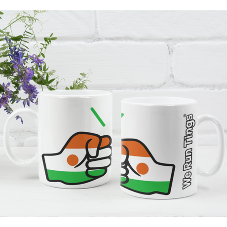 A pair of glossy white ceramic We Run Tings Niger tea, coffee mugs, cups with a graphic design of the brand and the colours of the flag of Niger. Side view with a white brick background.