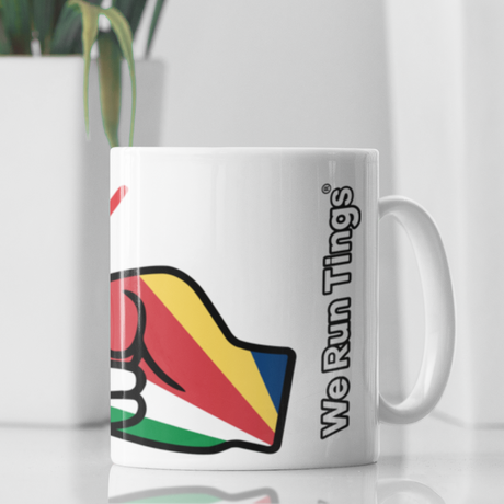We Run Tings White ceramic coffee mug with colorful Seychelles flag design and text on a reflective surface