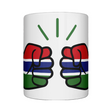Glossy white ceramic mug featuring a patriotic We Run Tings logo with two fists displaying the flag of Gambia on a white background.