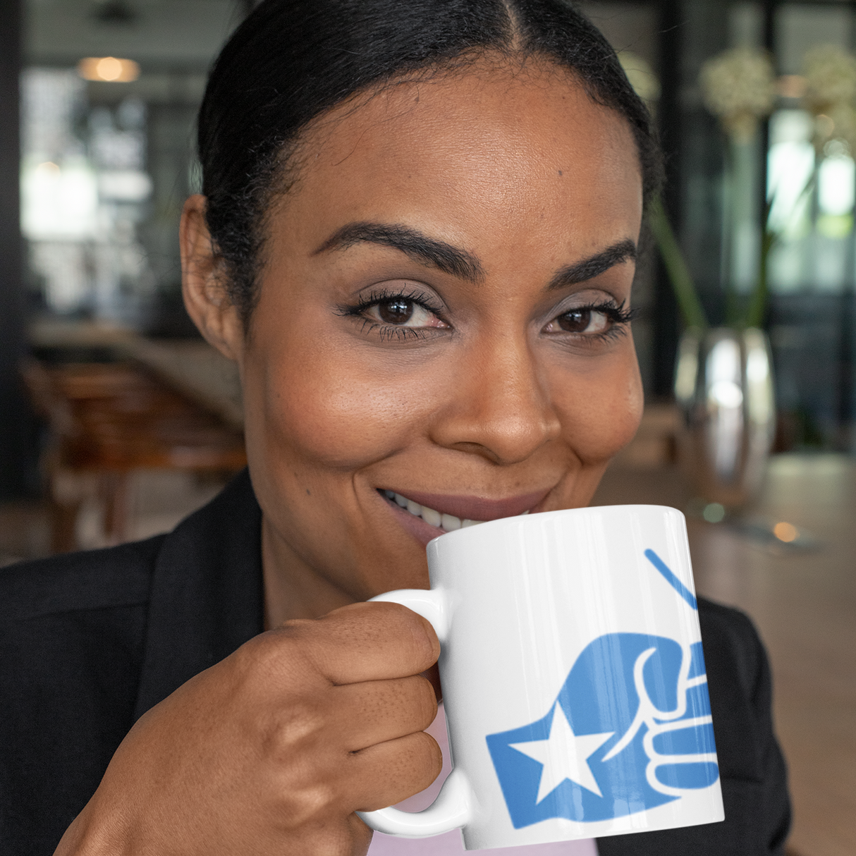 Woman smiling and holding a We Run Tings white ceramic tea, coffee mug featuring the flag of Somalia in the loge in an indoor setting