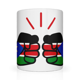 A white We Run Tings ceramic mug with a glossy finish featuring a graphic design of clenched fists and the flag of South Sudan. Front view.