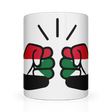 A glossy white ceramic We Run Tings, Sudan coffee, tea mug with a design of two fists on the side, representing the brand We Run Tings, and the flag of Sudan.